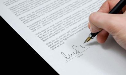 Main d'une personne qui signe un document contractuel illustrant les conditions pour rédiger un contrat valide.